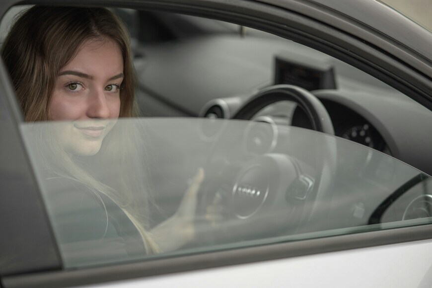 Devojka sedi u automobilu i drži volan