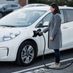 Žena priključuje električni automobil na stanici za punjenje