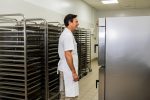 Muškarac u beloj kecelji stoji ispred velike industrijske pećnice