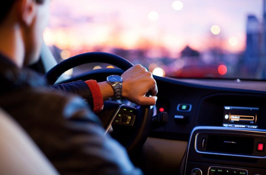 Unutrašnjost automobila sa vozačem koji se drži za volan