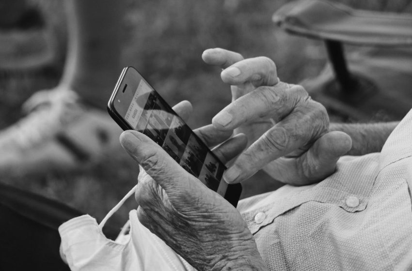 Osoba leži na kauču i koristi telefon