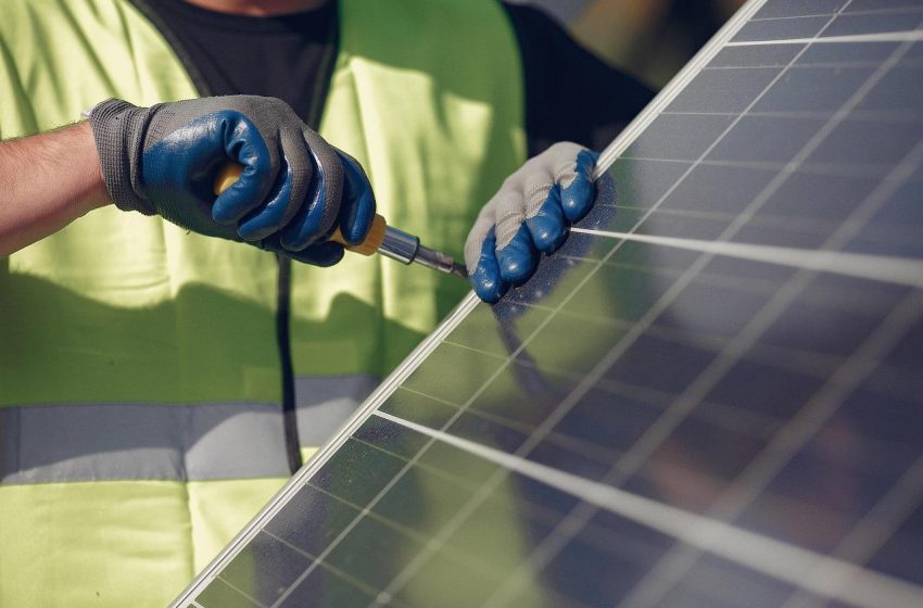 Radnik sa crnim rukavicama zateže šraf na solarnom panelu