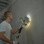 Muškarac u beloj majici radi na zidu u građevini u izgradnji